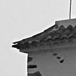 A white wall and a dark window under a tiled roof